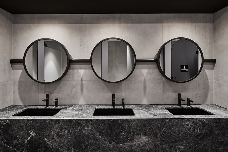 Photograph of a monochromatic commercial bathroom with luxurious marble and feature LED lighting